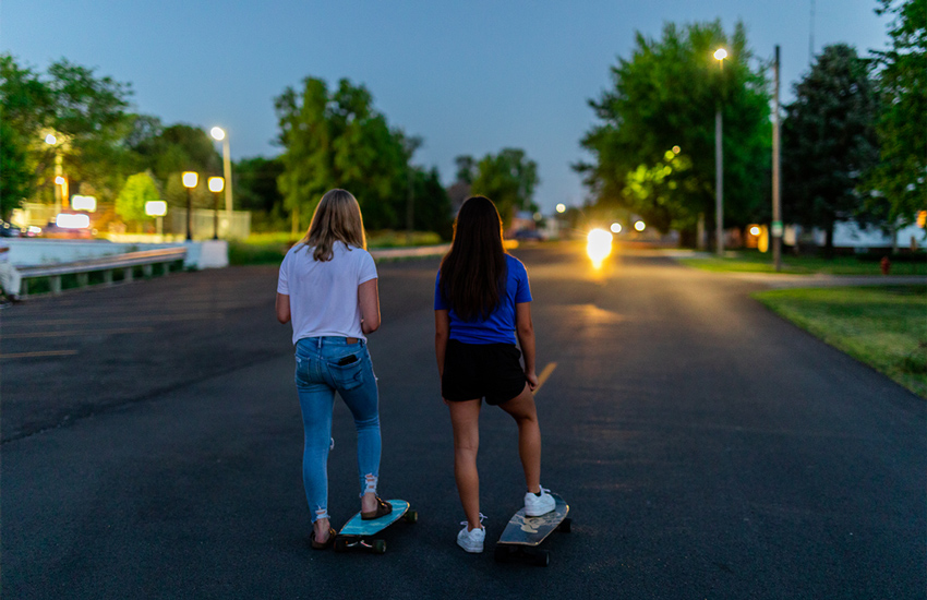 Two girls longboarding down the road